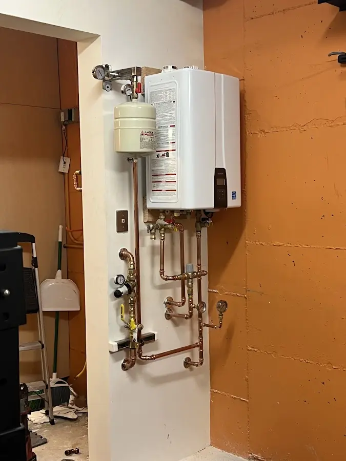 Plumbing technician inspecting water heater connections in South Beloit